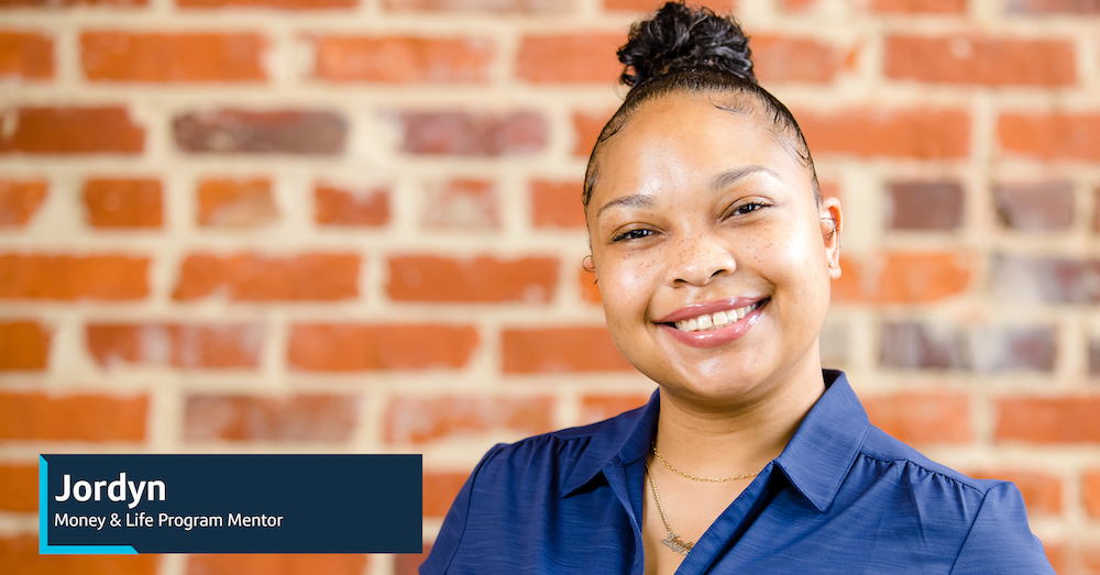 Image of Capital One associate Jordyn standing in front of a brick wall with their title: Jordyn, Money & Life Program Mentor
